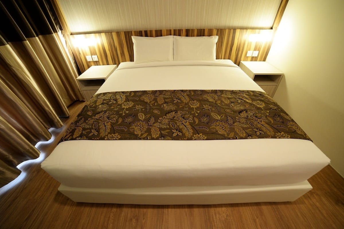Une chambre d’hôtel avec un grand lit, deux tables de chevet et une tête de lit dotée d’un luminaire.