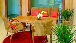 Een eethoek met een houten tafel, rieten stoelen en een rood vloerkleed.