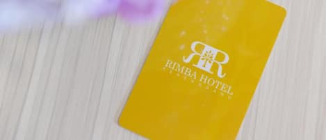 A yellow hotel tag with the name 'RIMBA HOTEL' on a wooden surface.