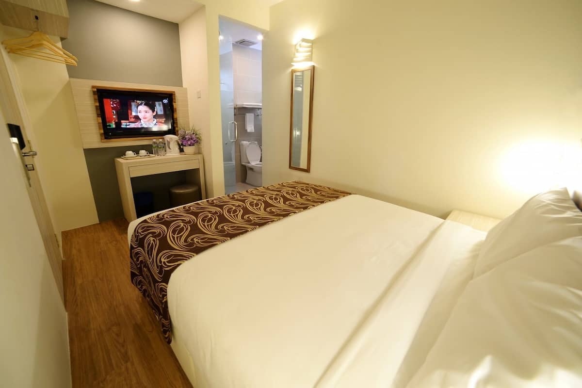 Une chambre d’hôtel comprenant un lit, une télévision, un bureau avec un miroir et une salle de bain.