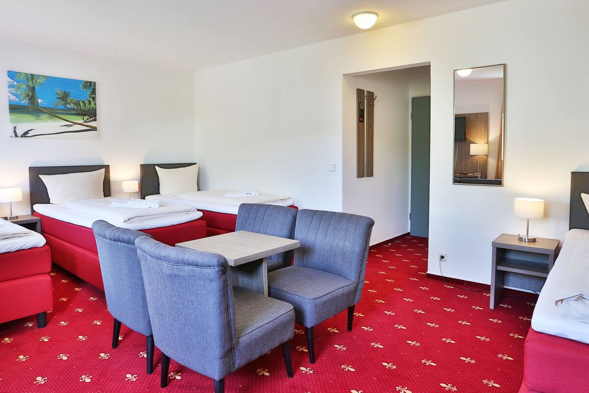 A hotel room with two beds, a dining table, and a seating area with chairs.