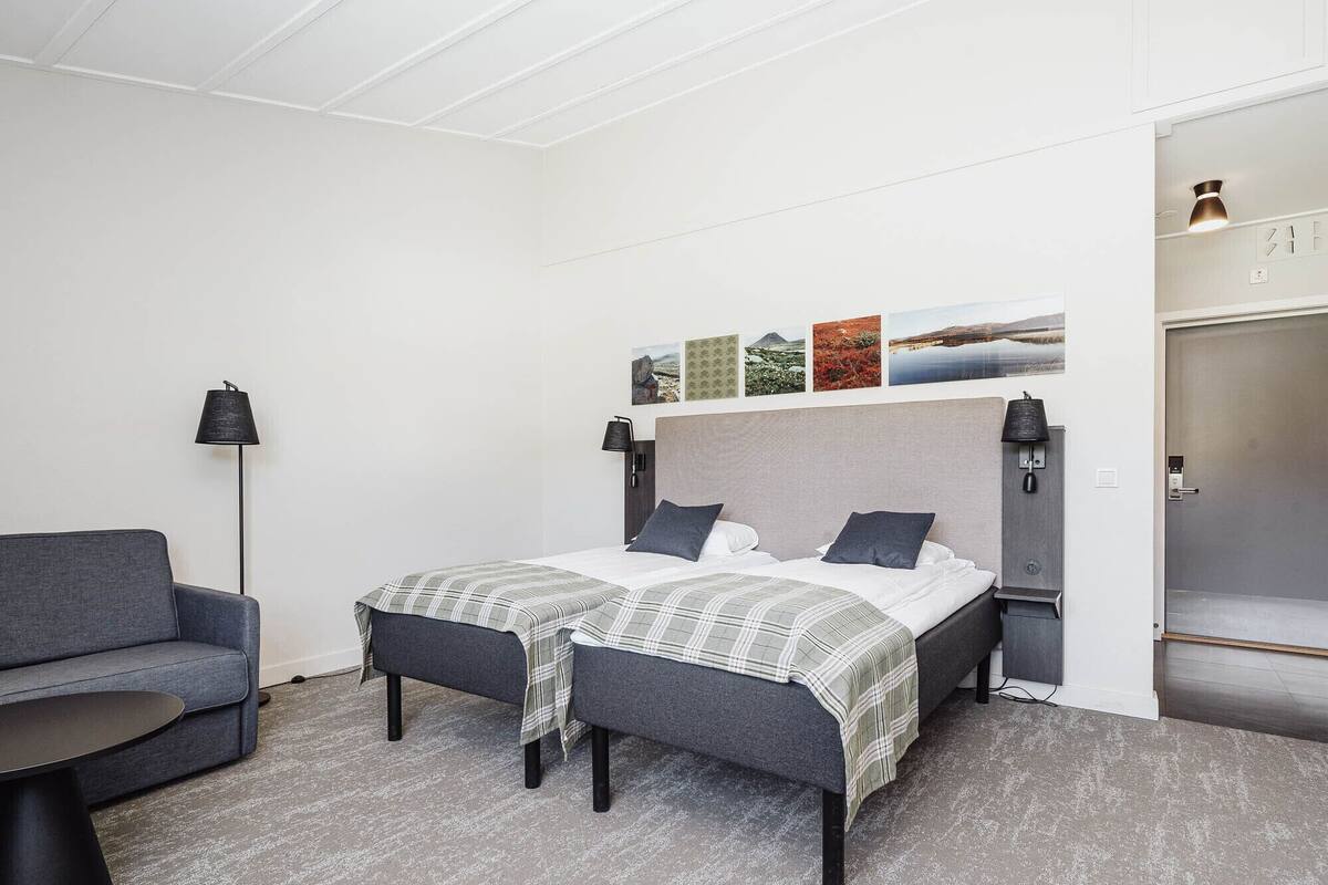 A bedroom with a bed, two bedside tables, a chair, a floor lamp, and a wardrobe.
