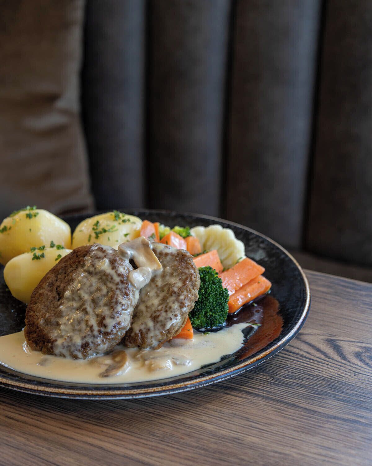 A plate of food with meatballs, potatoes, carrots, and broccoli.