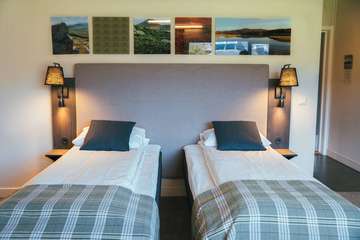 A hotel room with two beds, a large headboard, and wall-mounted artwork.