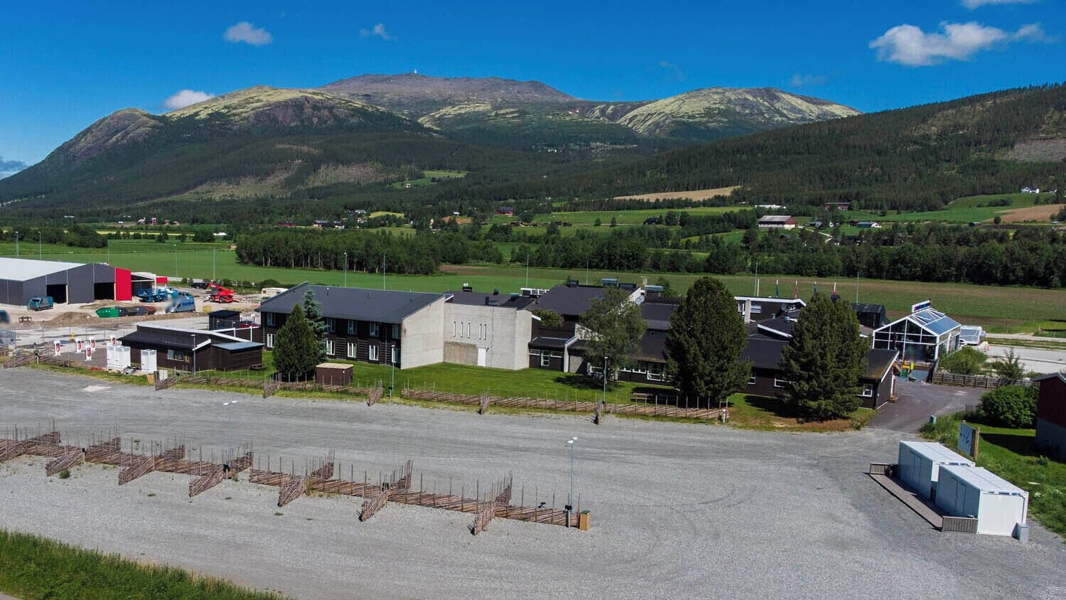 A commercial building with a parking lot, surrounded by residential houses and mountains.