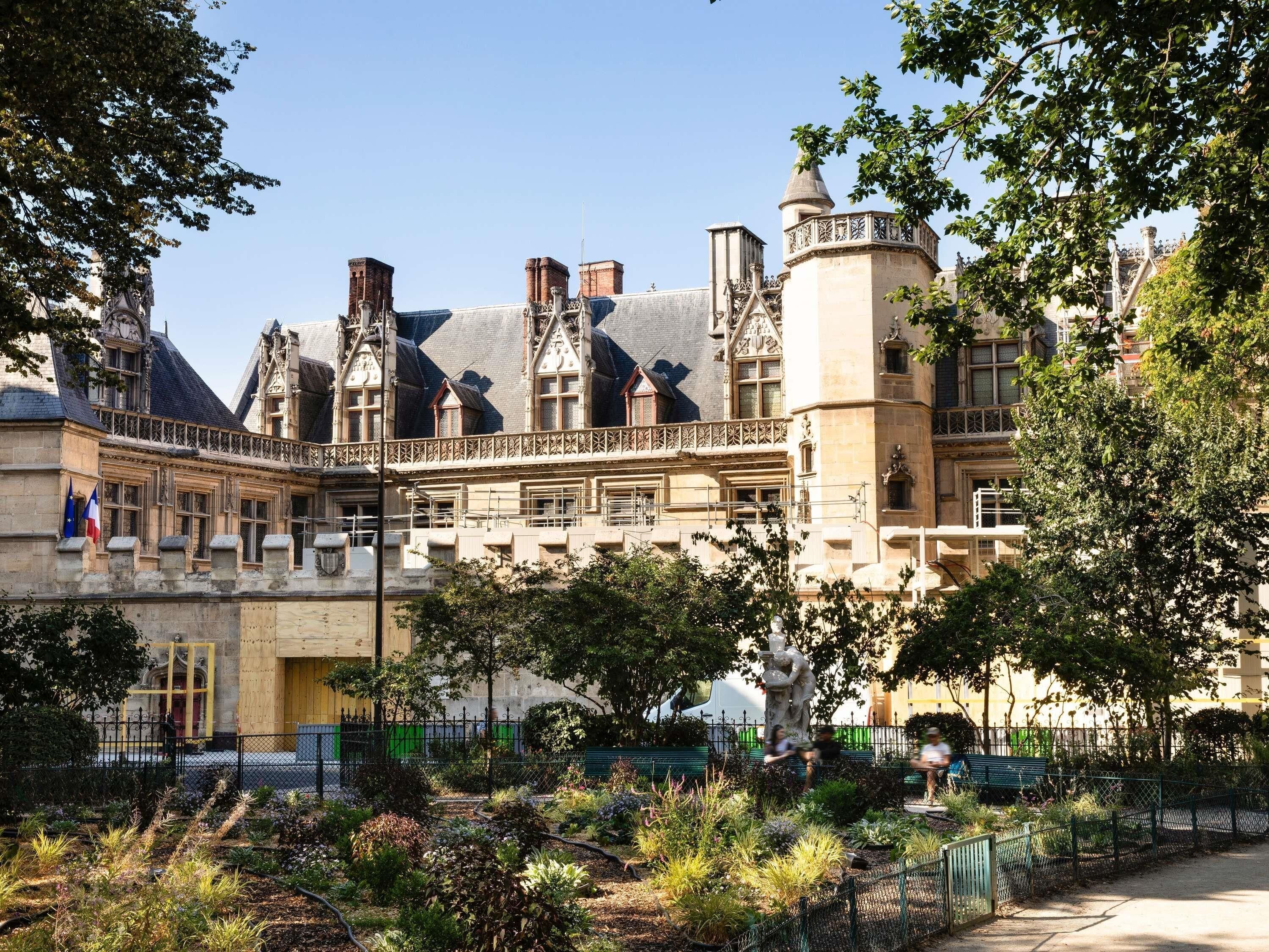 A historic building with a courtyard, a statue, and a flag.
