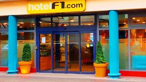 A hotel entrance with a glass door, blue pillars, and potted plants.