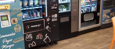 A row of vending machines with various food and drink options, including a machine with a 'Payez Mangéz' sign.