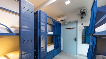 Habitación tipo dormitorio con literas, una puerta y un ventilador.