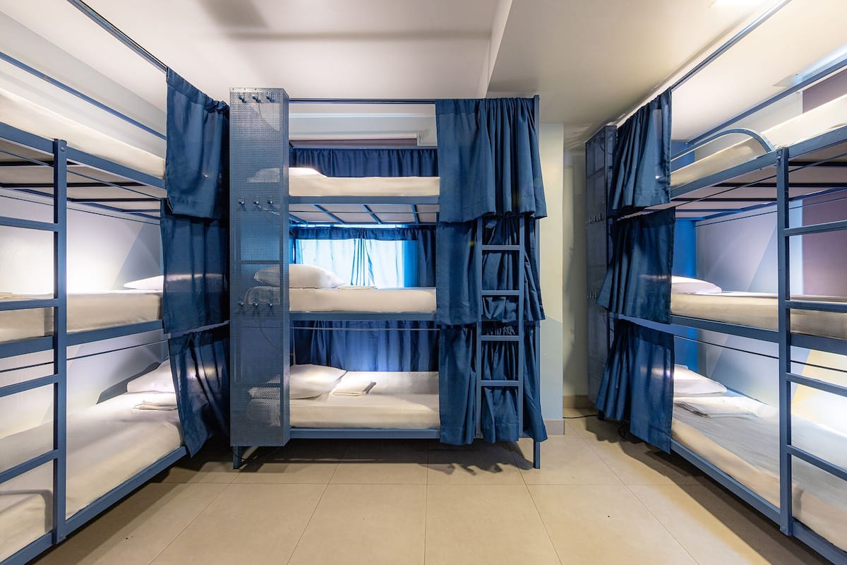Um dormitório com beliches, escada e cortinas.
