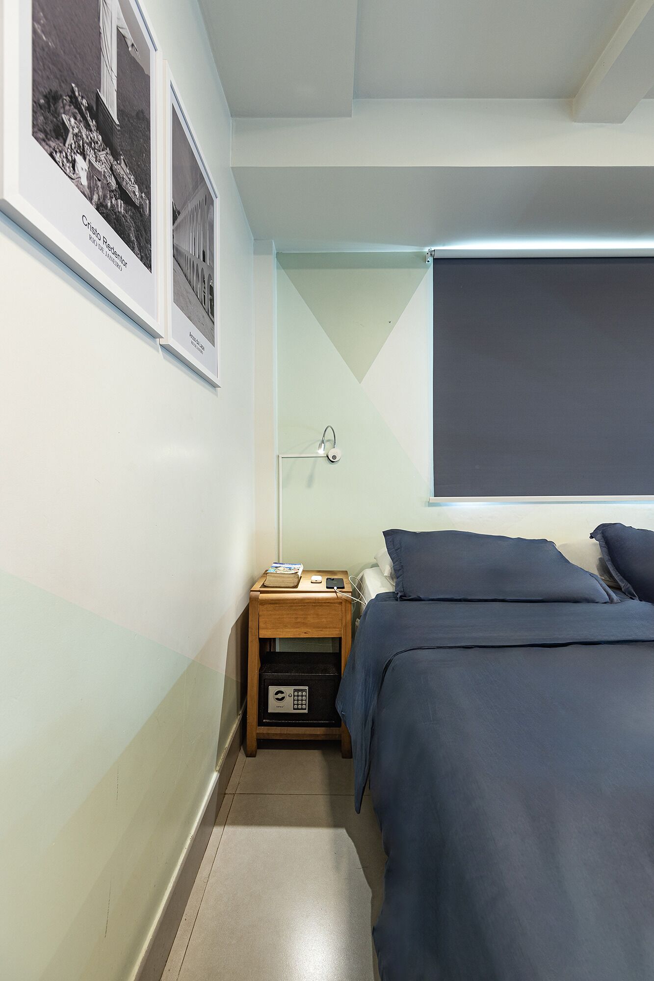 A bedroom with two beds, a nightstand with a lamp, and framed pictures on the wall.