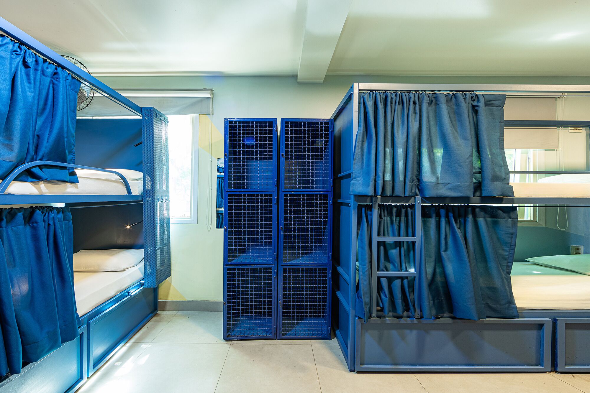 A dormitory room with bunk beds, a window, and a door.