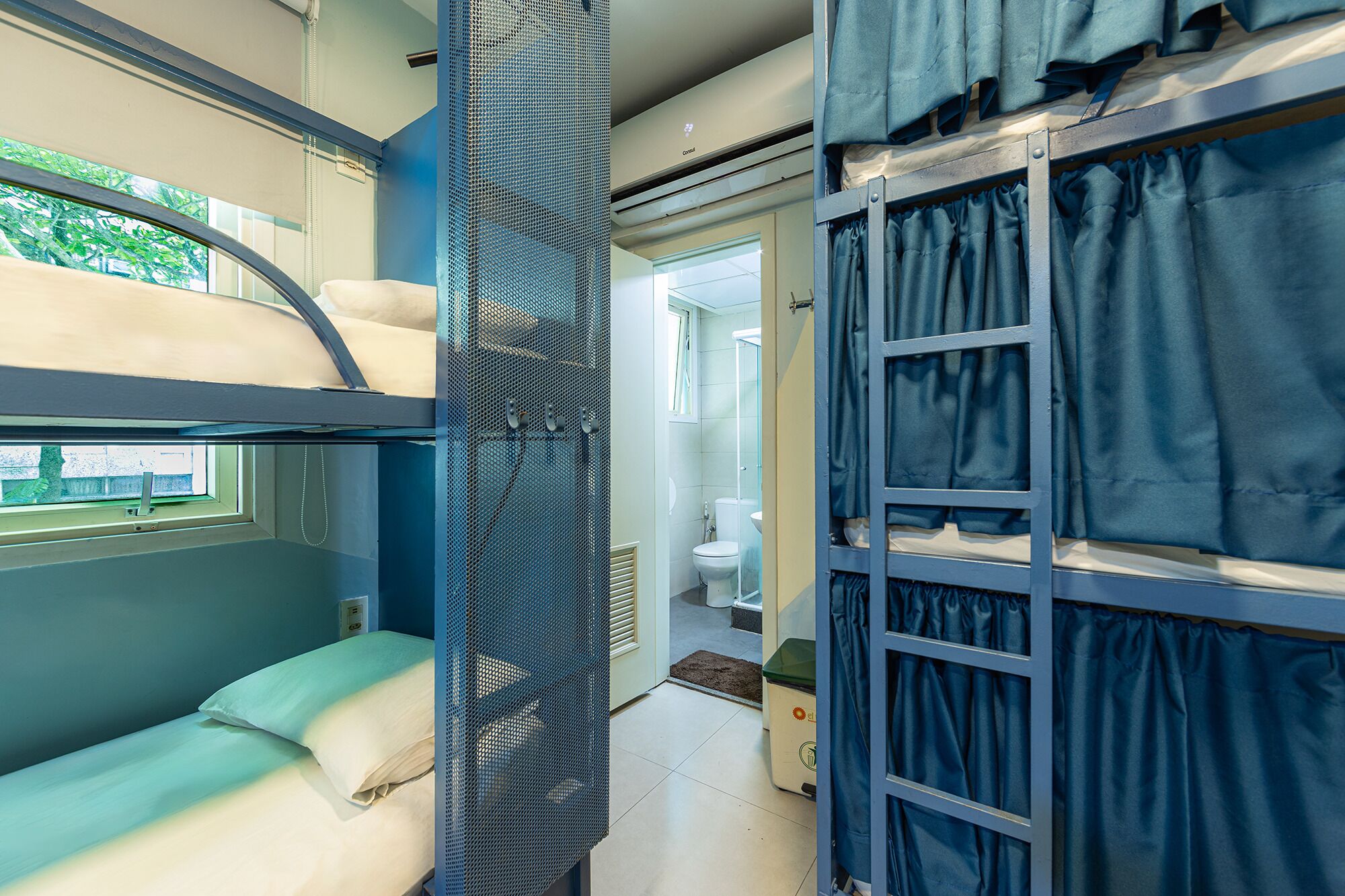 Habitación con literas, ventana, baño con inodoro y ducha, y espacio de almacenamiento.