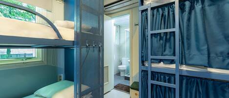 Habitación con literas, ventana, baño con inodoro y ducha, y espacio de almacenamiento.
