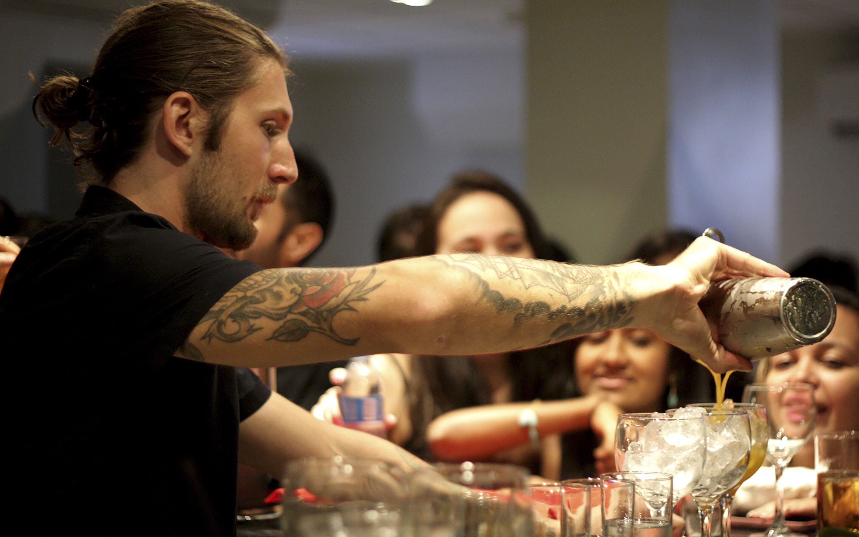A bartender pouring a drink into a glass.