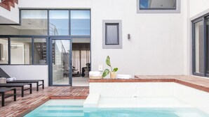 Ein moderner Poolbereich im Freien mit Holzterrasse, einer Patio mit Glasverkleidung und einem kleinen Whirlpool.