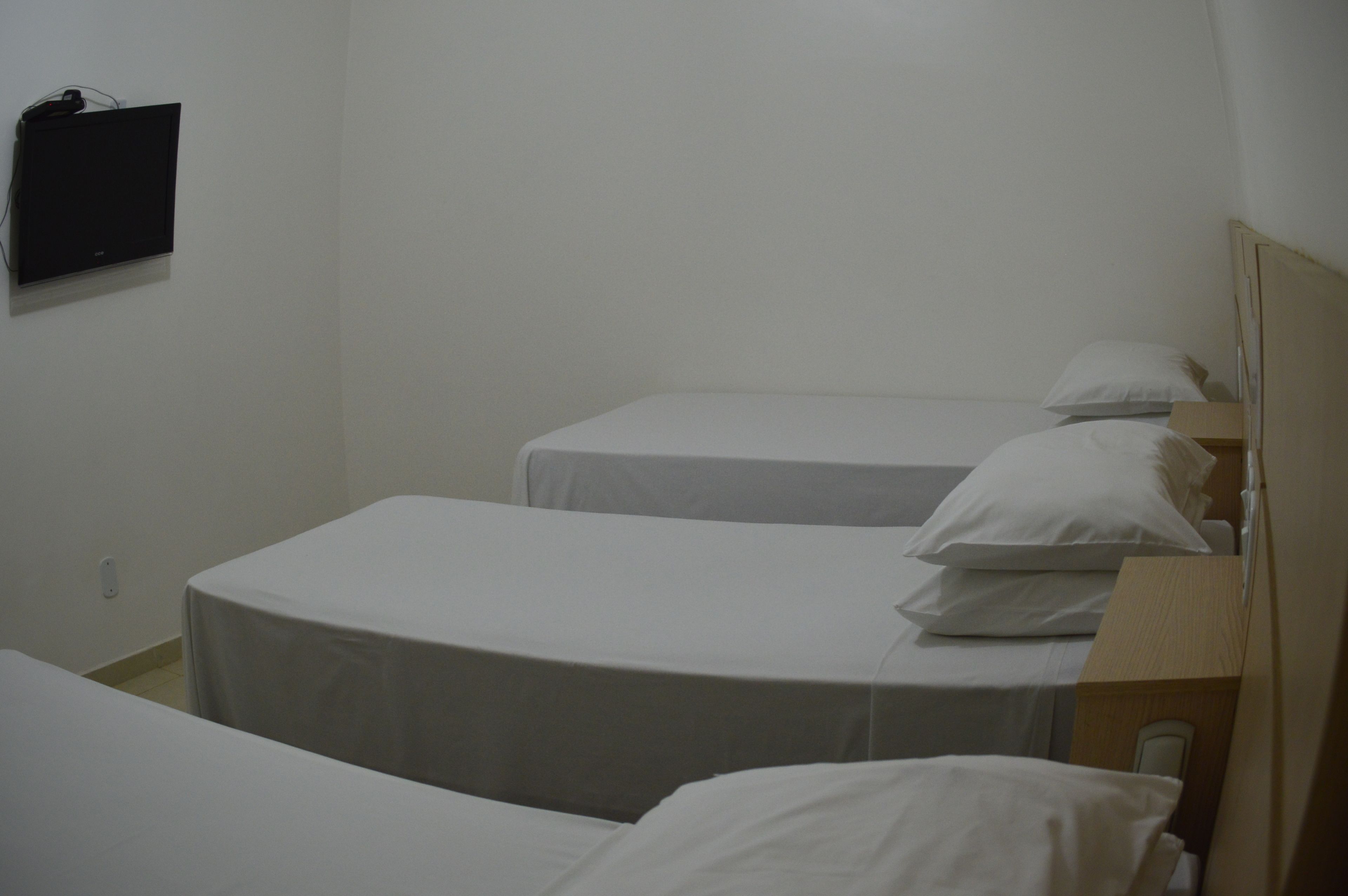 Una camera d'albergo con due letti singoli, un comodino e una TV a parete.