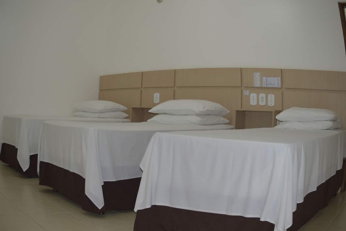 A hotel room with two single beds, each with a white bedspread and brown headboard.