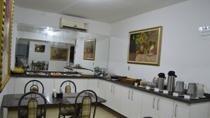 Una cucina con mobili bianchi, un tavolo da pranzo con sedie e diversi elettrodomestici e utensili.