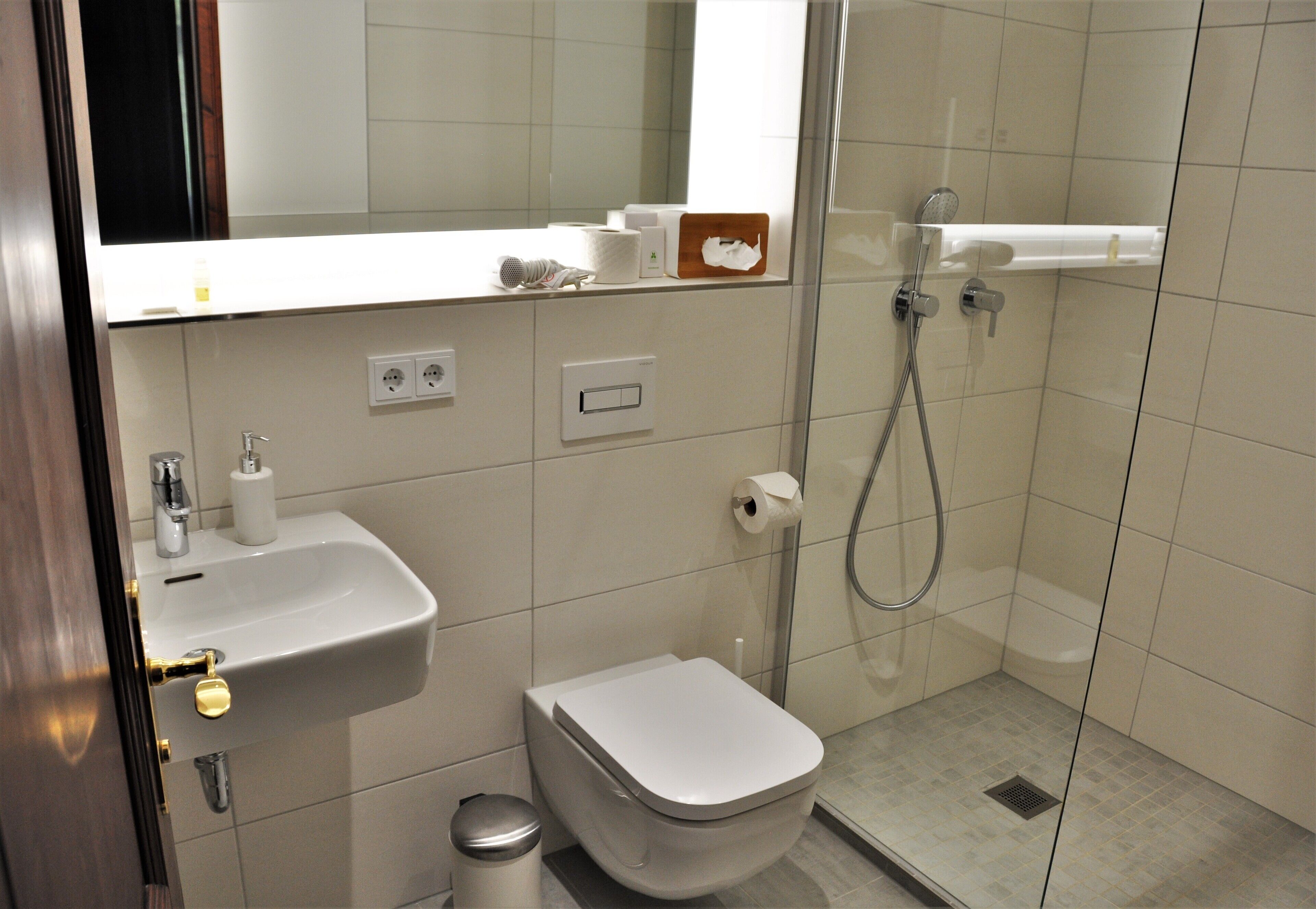 A modern bathroom with a sink, toilet, and glass-enclosed shower area.