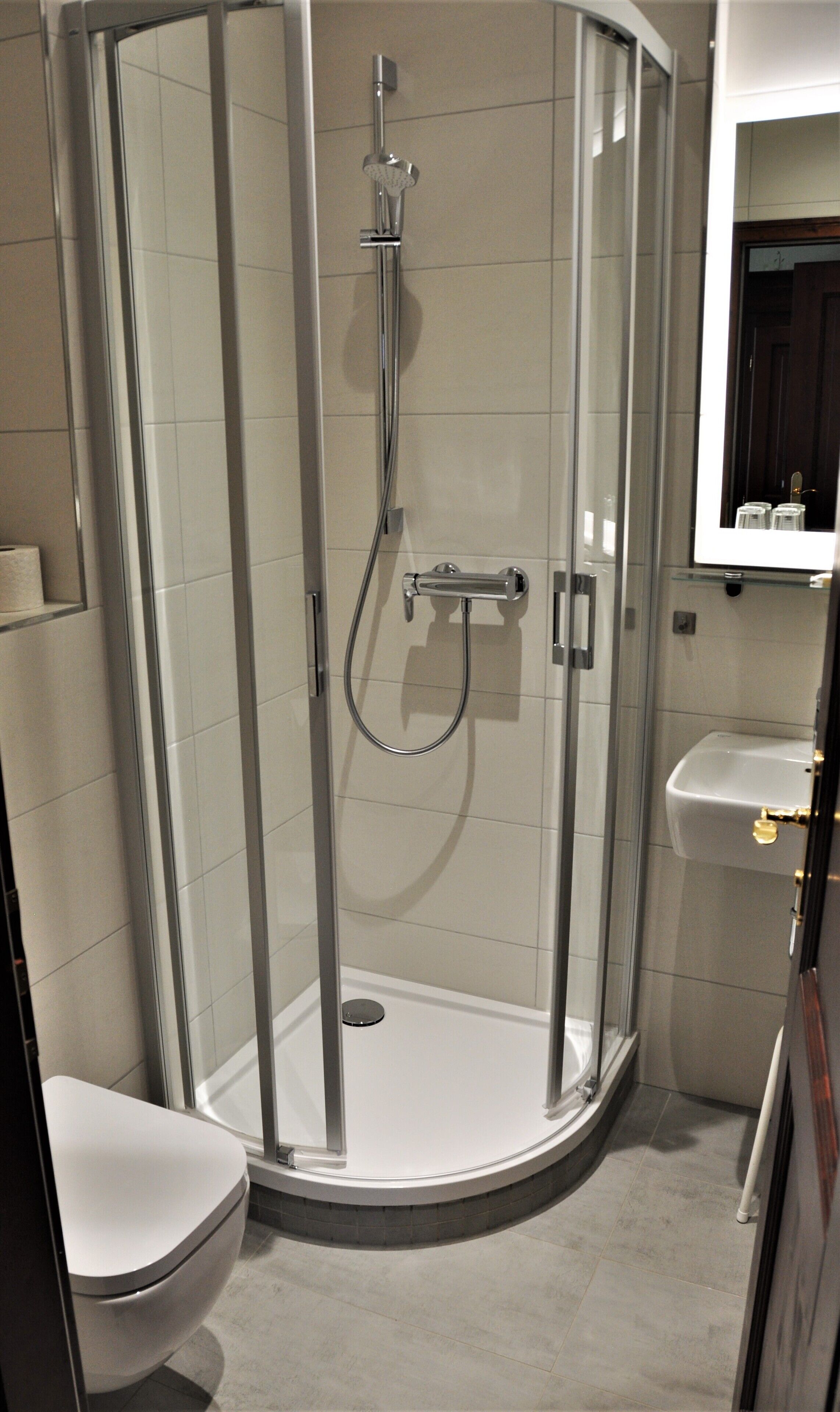 Ein Eckbad mit Duschkabine, Toilette und Waschbecken.