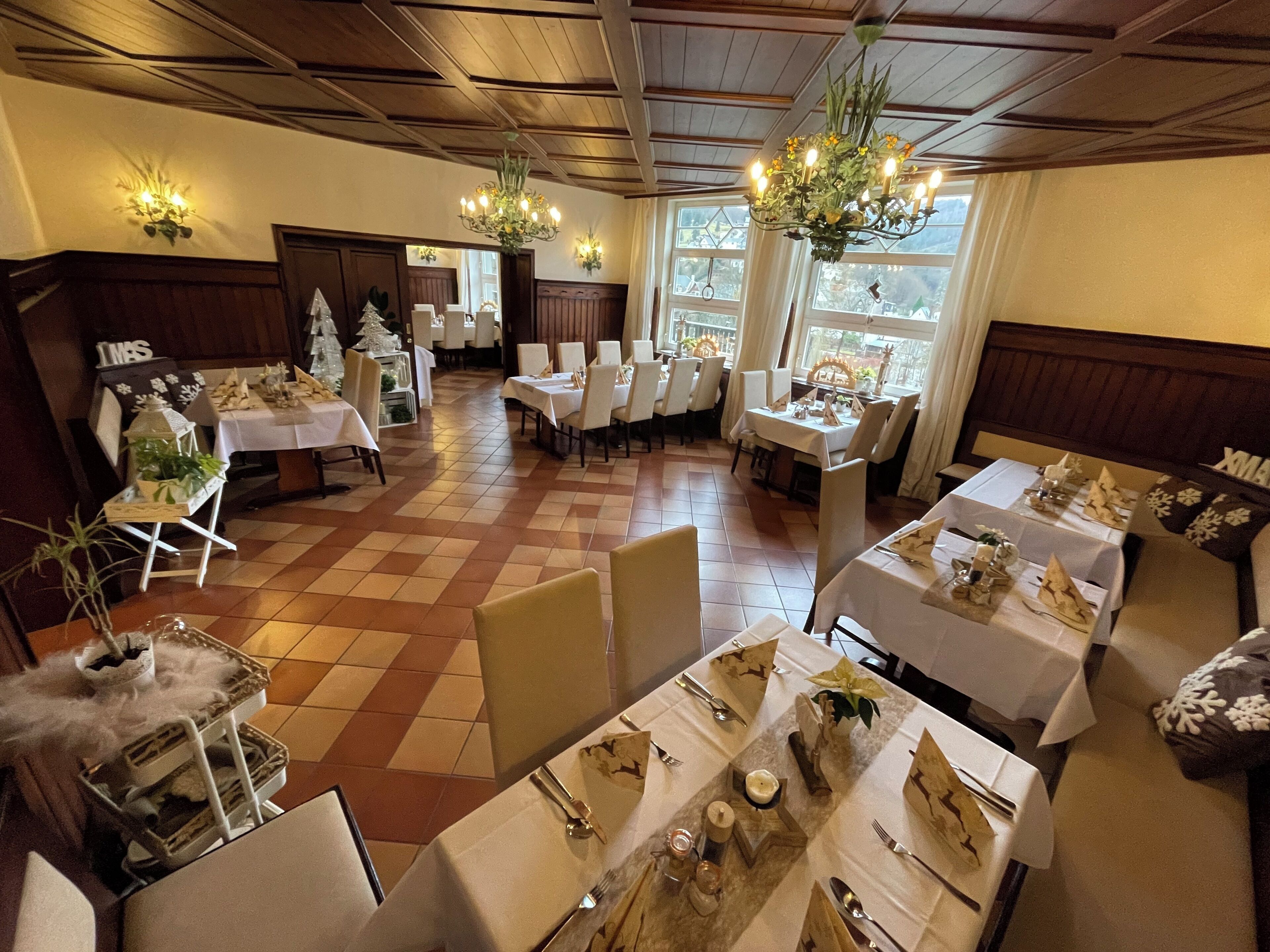 Un espace repas avec plusieurs tables dressées pour le repas, agrémenté de nappes blanches et de couverts disposés avec soin.