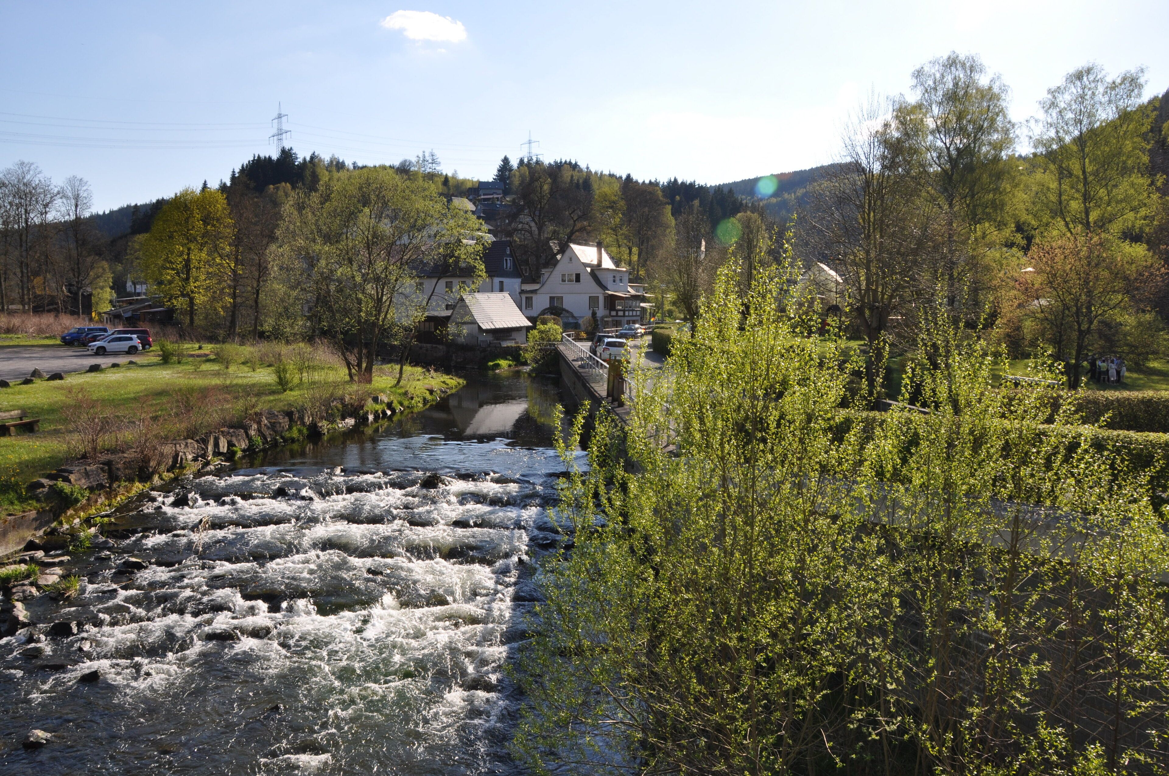 Un río con un puente, rodeado de vegetación y edificios.