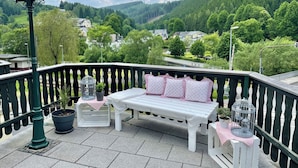A balcony with a white bench, two birdcages, and potted plants. - Flair Hotel Waldfrieden (Schwarzatal)