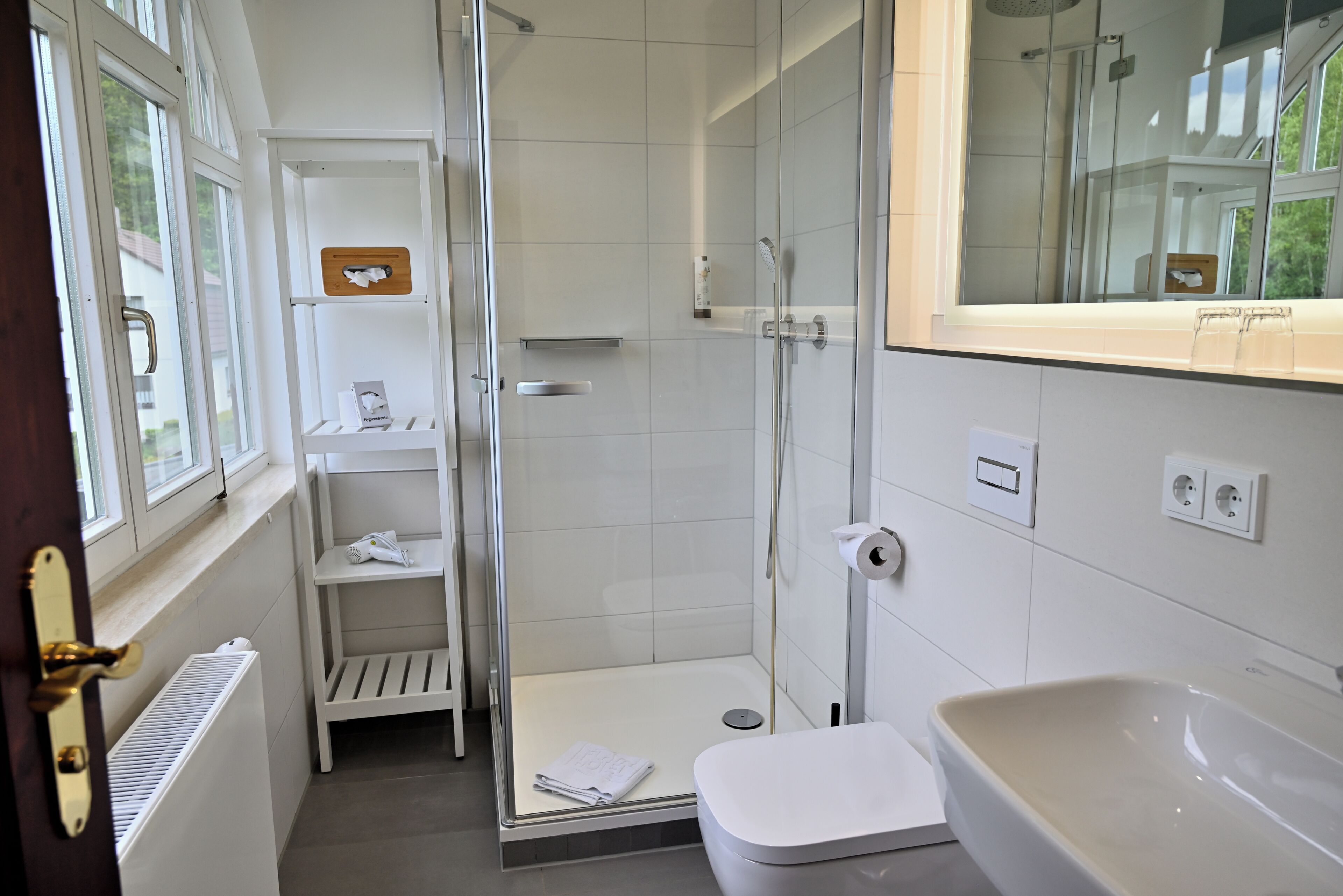 Ein modernes Badezimmer mit Duschkabine aus Glas, einer weißen Toilette und einer Badewanne.