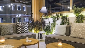 A modern lounge area with a sofa, two round wooden tables, and a lamp.