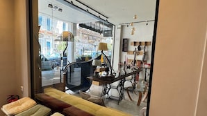 A modern interior with a large window, a bench with cushions, and a table with a lamp.