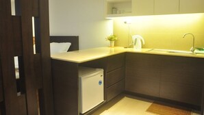 A compact kitchen with a built-in refrigerator, a sink, and a countertop. - AL-Aidid Homestay (Kota Bharu)
