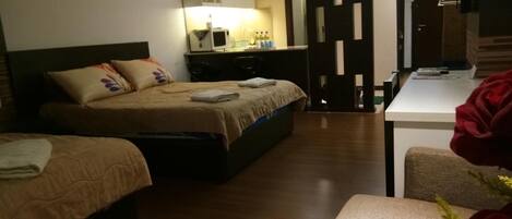 A hotel room with two beds, a desk, a chair, and a mirror.