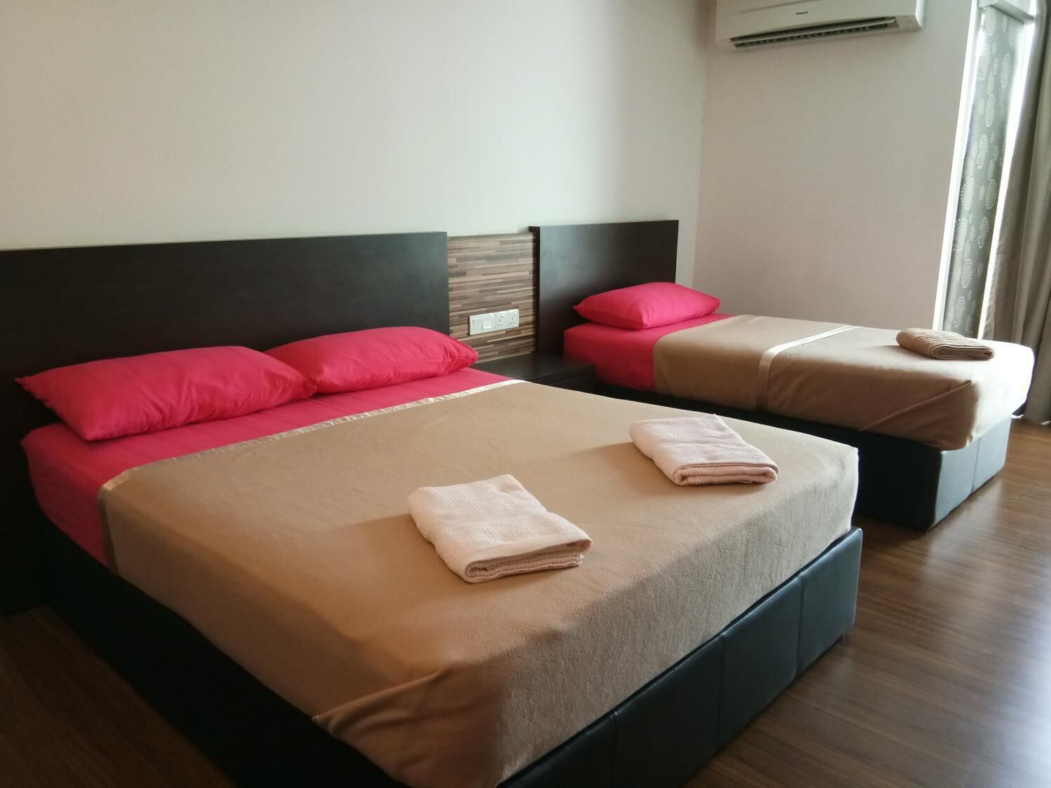 Una habitación de hotel con dos camas, cada una con cabecero, y una ventana con cortinas.