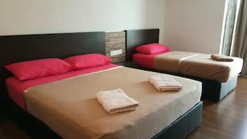 Una habitación de hotel con dos camas, cada una con cabecero, y una ventana con cortinas.