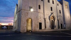 A large, historic building with a prominent central entrance and arched doorways, surrounded by a paved area. - Il Trespolo degli Angeli (Bari)
