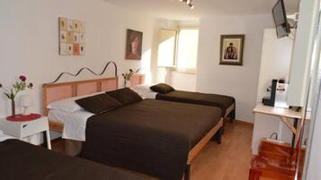 A bedroom with two single beds, a bedside table with a lamp, a chair, and a TV on a stand.