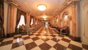 A grand hallway with a checkered floor, ornate columns, and elegant seating areas. - Borjomi Palace (Borjomi)