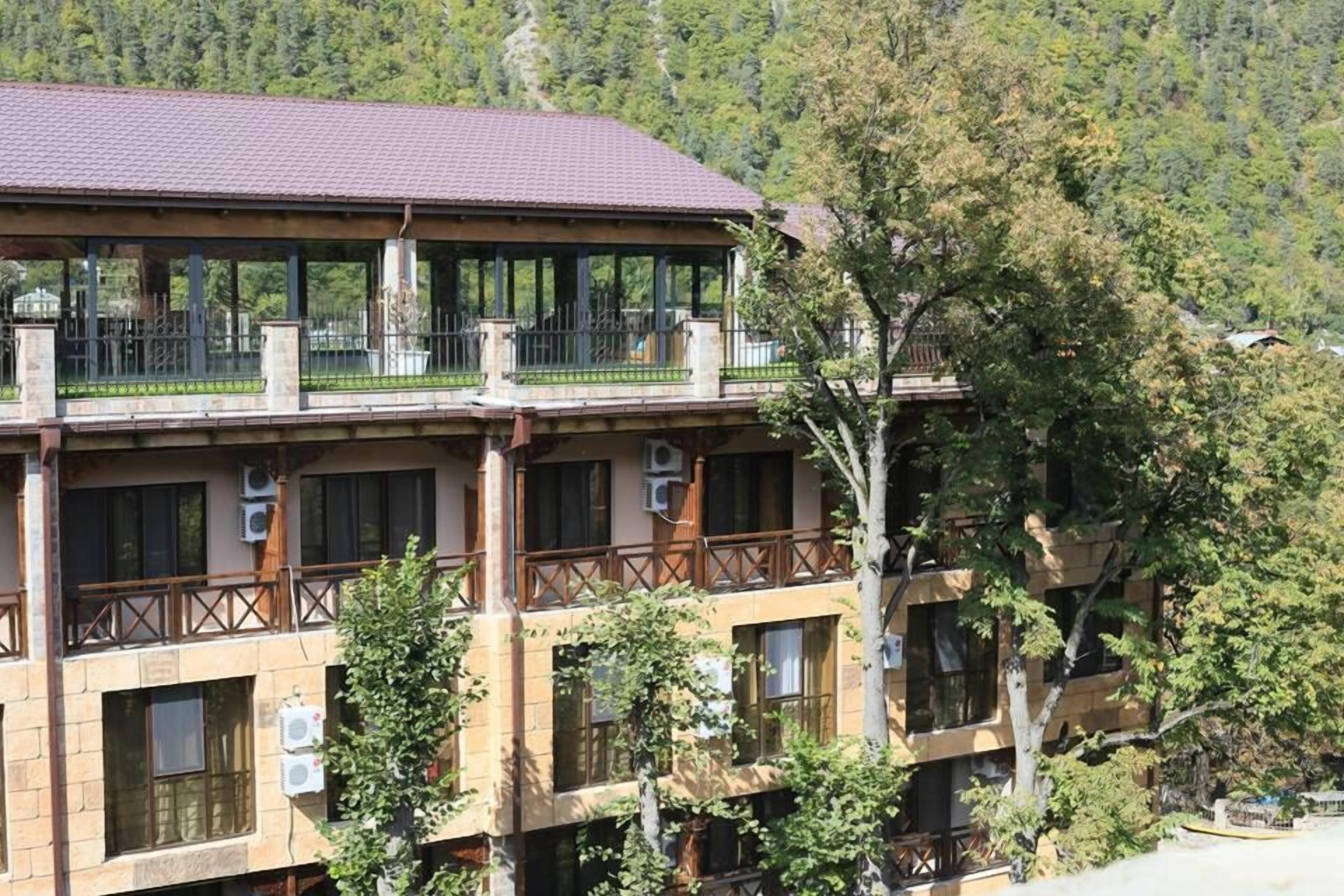 A multi-story building with balconies, air conditioning units, and a mountainous backdrop.