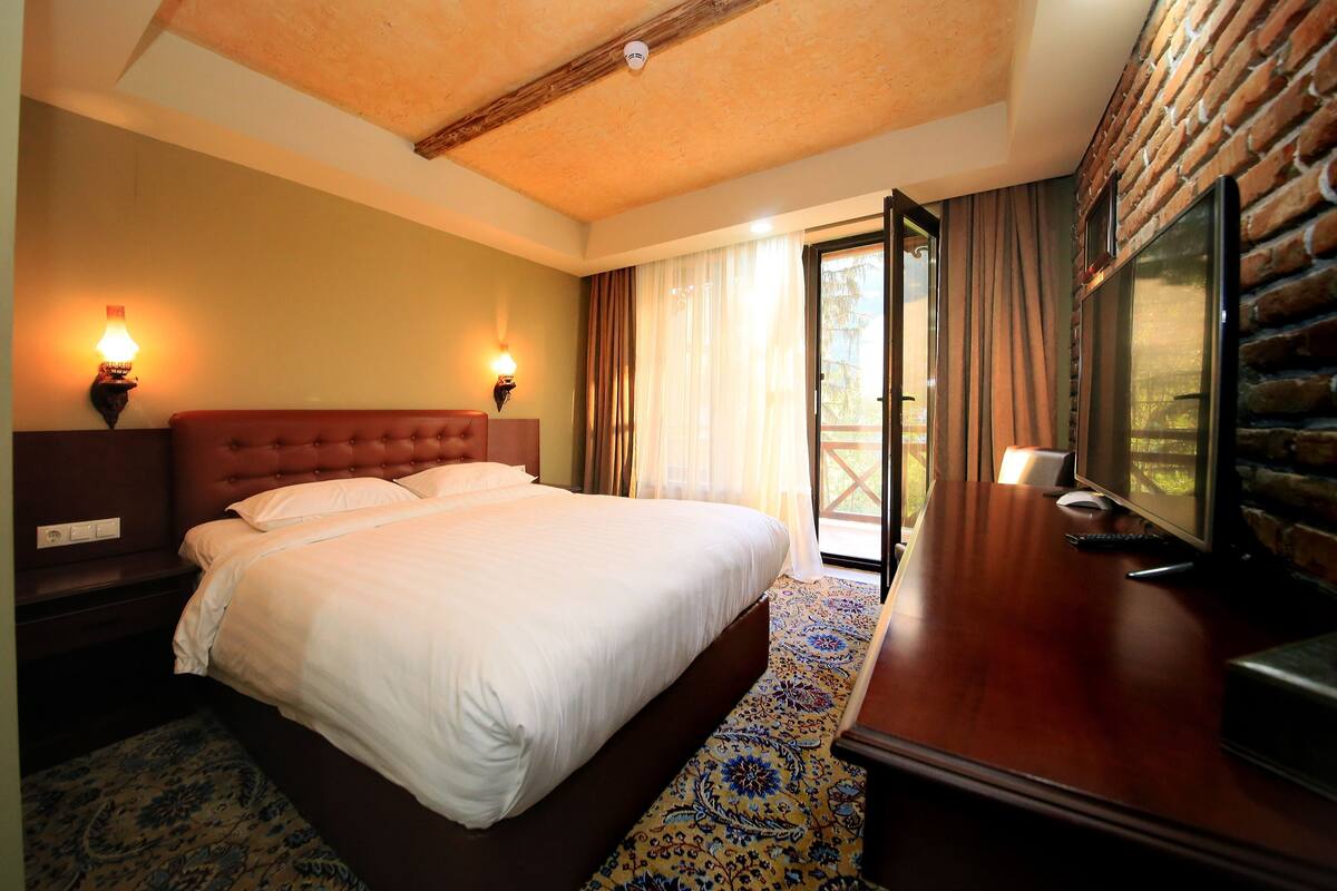 Una habitación de hotel con una cama grande, un escritorio con computadora y televisión.