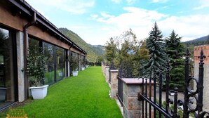 A pathway leading to a building with large windows, surrounded by greenery and a mountainous backdrop. - Borjomi Palace (Borjomi)