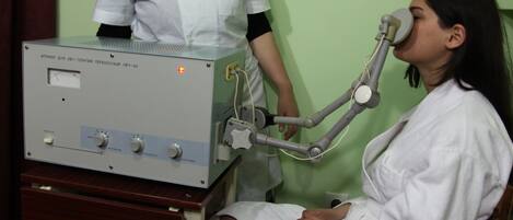 A medical examination room with a patient seated and a medical device being used.