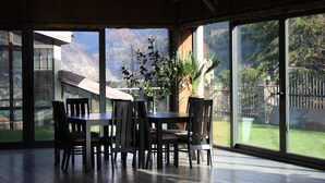 A dining area with a table and chairs, large windows, and a potted plant. - Borjomi Palace (Borjomi)