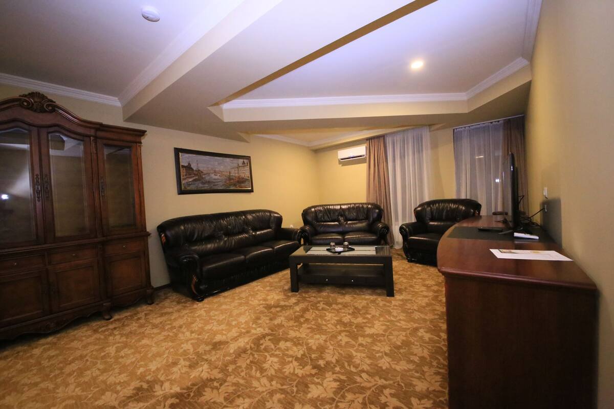 A living room with two leather sofas, a coffee table, a wooden cabinet, and a painting on the wall.