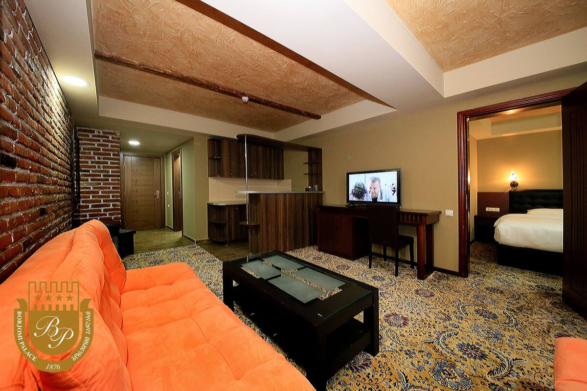 A hotel room with a billiards table, a sofa, a television, and a bed.