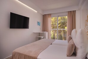 Une chambre d’hôtel avec un lit, un téléviseur à écran plat, une fenêtre avec des rideaux et une vue sur les arbres.