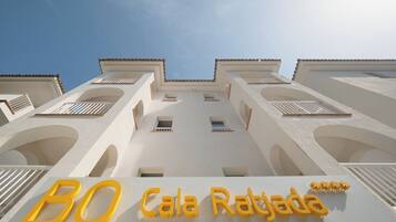 Fachada de hotel con balcones y un cartel que dice 'BQ Cala Rajada'.