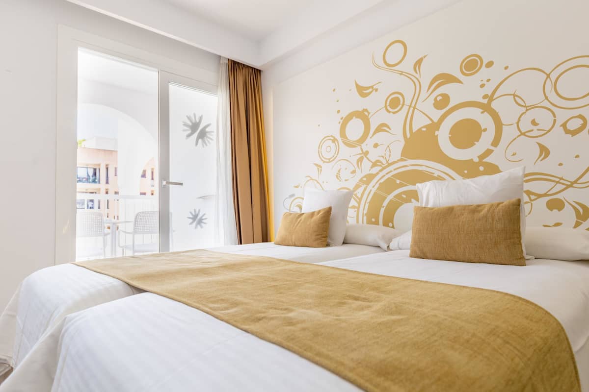 Ein Hotelzimmer mit einem großen Bett, Blick ins Freie und einer dekorativen Wand.