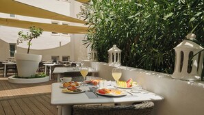 Un área de comedor al aire libre con mesas, sillas y una variedad de comida y bebidas.