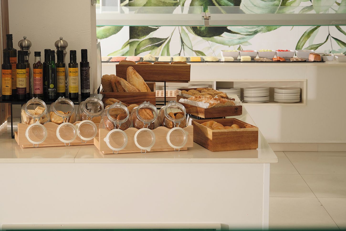 A breakfast buffet with various breads, pastries, and condiments.